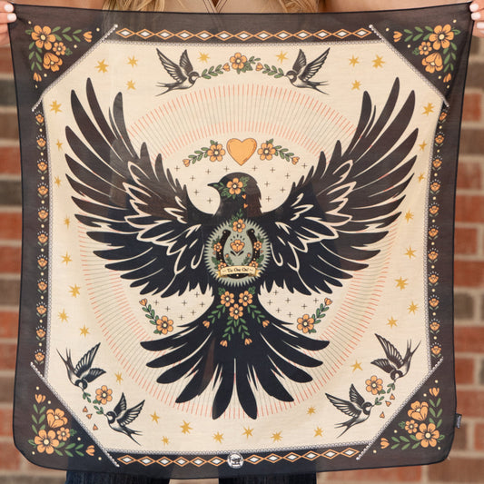 Decorative square with a black bird design held against a brick wall.